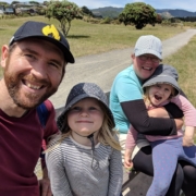 Smiling family wearing hats outside in the sun with gravel track and grass