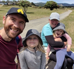 Smiling family wearing hats outside in the sun with gravel track and grass